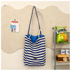 Detail view of a striped canvas tote bag with long straps and a blue interior lining