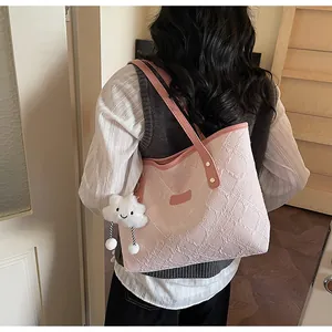 Detalle de bolso tote rosa texturizado con colgante de nube y correa de cuero fino