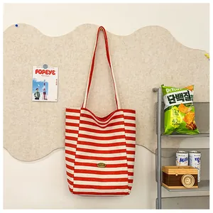 Detailed view of red and white striped canvas tote bag with a leather logo patch