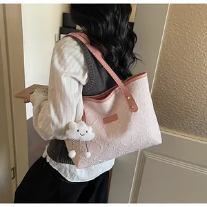 Detalle de bolso tote rosa con bordado geométrico y colgante de nube blanca de felpa