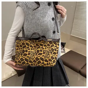 Leopard and rose print canvas handbag with brown straps shown in indoor lifestyle setting