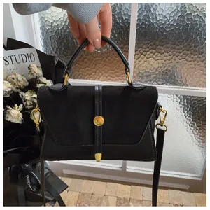Details der schwarzen Leder- und Wildledertasche mit goldener Schnalle und Tragegriff