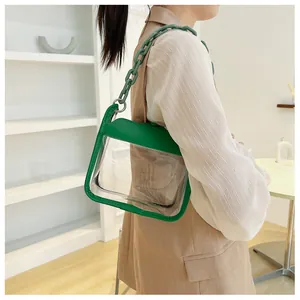 Detail shot of a transparent crossbody bag with green leather trim and chunky chain strap