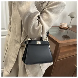 Detail einer klassischen schwarzen Ledertasche mit goldenem Drehverschluss und Schultergurt