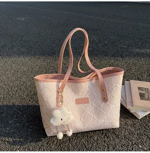 Detalle de bolso tote rosa acolchado con textura floral y colgante de nube suave