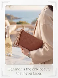Brown woven wristlet wallet with gold zipper shown on a scenic coastal terrace
