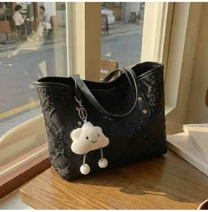 Detalle de bolso tote negro acolchado con lentejuelas y colgante de nube de felpa blanca