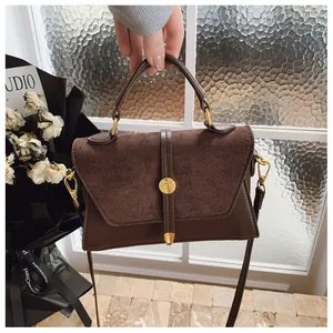 Detail einer braunen Ledertasche mit goldener Hardware und Wildleder-Patchwork-Design