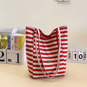 Classic red and white striped canvas tote bag with woven rope straps and metal plaque
