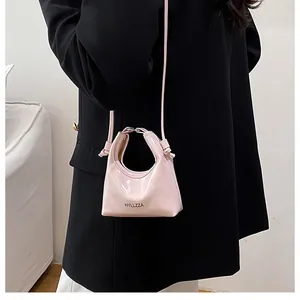 Detailed view of a mini pink glossy dumpling bag worn over a black blazer for daily style