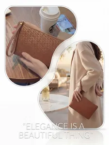 Detail of a brown woven texture clutch bag with wristlet strap and golden zipper closure
