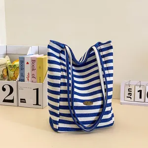 Blue and white striped canvas tote bag with handmade metal logo and sturdy handles