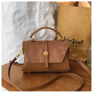 Braune Retro-Handtasche aus Kunstleder und Wildleder auf einem rustikalen Holztisch