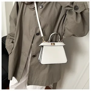 Nahaufnahme der weißen Trapez-Ledertasche mit Metalldrehverschluss und Akkordeonfalten