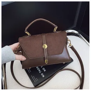 Detail einer braunen Ledertasche mit matter Wildlederklappe und goldenem Metallverschluss