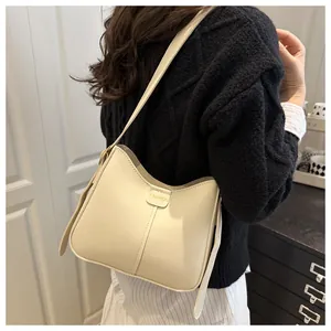Chic cream hobo bag with gold Fashion lettering worn over the shoulder on black knitwear