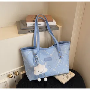 Detalle del bolso tote azul claro con bordado floral y colgante de nube blanca de felpa