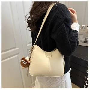 Detail of off-white bucket bag with a FASHION leather tag and a brown fuzzy charm