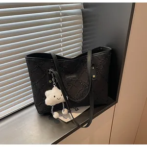 Detalle del bolso tote plisado negro con costuras de diamante y colgante de nube blanca