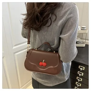 Sac sous le bras marron avec boucle cerise en strass rouges dans un décor moderne