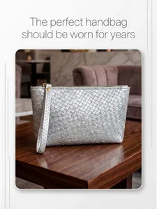 Macro shot of silver woven clutch bag with gold zipper detail on dark wood surface