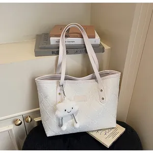 Detalle del bolso tote crema floral con asas de cuero rosa y un colgante de nube suave