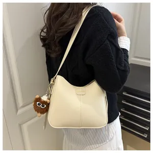 Detail of cream PU bucket bag with 'FASHION' label and brown plush monster pendant