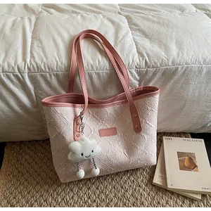 Detalle del bolso tote rosa con textura floral, asas de cuero y colgante de nube