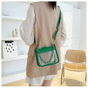 Detail of transparent PVC crossbody bag with green faux leather trim and chunky chain