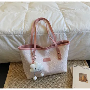 Bolso tote rosa con relieve y colgante de nube de felpa sobre estera tejida
