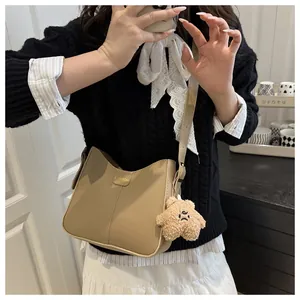 Fashionable beige bucket bag with cute bear charm and golden logo on model