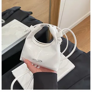 Detailed view of white mini dumpling bag with gathered handle and HYLLZZA logo