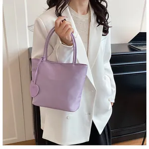 Chic lavender tote bag with heart charm shown on model in a modern office setting