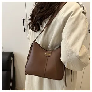 Detail of brown leather bucket bag with gold fashion label on a beige trench coat
