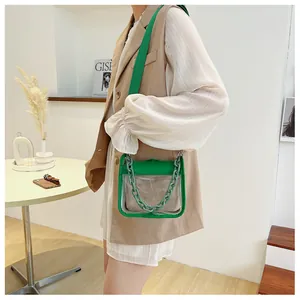 Detail of transparent PVC small square bag with green leather trim and chain strap