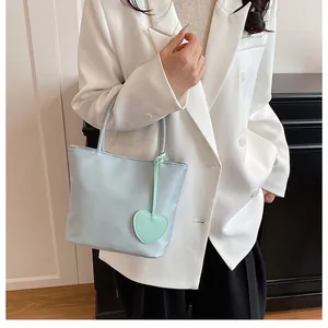 Close-up of mint green tote bag featuring a heart leather charm and thin round handles