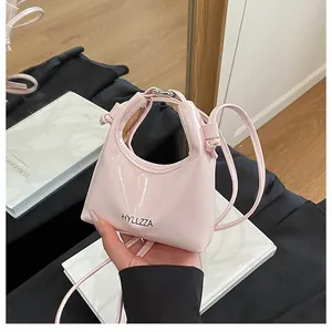 Detail of a pink patent leather mini crossbody bag with glossy finish and brand logo