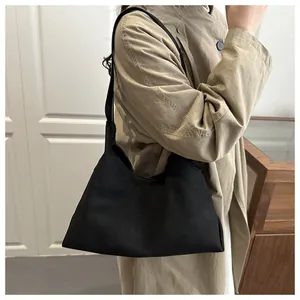 Nahaufnahme einer minimalistischen schwarzen matten Schultertasche zum beigen Trenchcoat