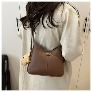 Detail view of brown vintage bucket bag with Fashion gold logo and plush charm accessory