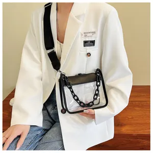Close-up of a clear PVC square bag with black chain and wide shoulder strap on a model