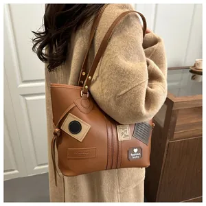 Detail of vintage brown PU leather tote bag with fashion patches worn on shoulder