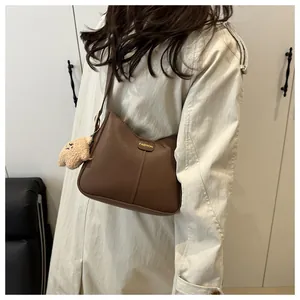 Detail of dark brown bucket bag with gold lettering and cute plush bear charm on strap