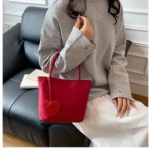 Close-up of a red nylon tote bag featuring a heart pendant in a chic lifestyle setting