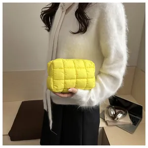 Detail of bright yellow quilted nylon makeup bag with soft padded texture and zipper