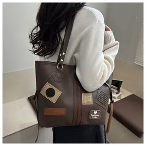 Detail of adjustable golden buckle and decorative patches on large brown PU tote bag