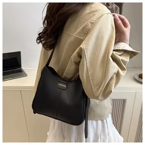 Detail of black matte leather shoulder bag with gold FASHION letter buckle and sleek strap