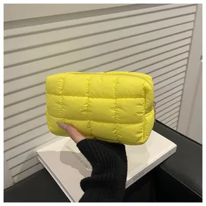 Detailed view of yellow quilted nylon cosmetic bag with soft puffy checkered texture