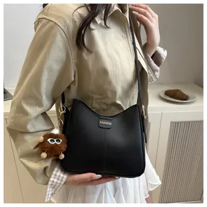 Detail of black faux leather bucket bag with Fashion lettering and plush monster charm