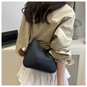 Detail of black faux leather bucket bag with fashion plaque and plush monster charm