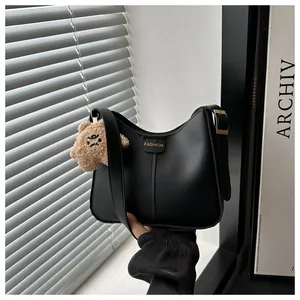 Detail of black matte PU leather bucket bag with fashion label and brown teddy charm
